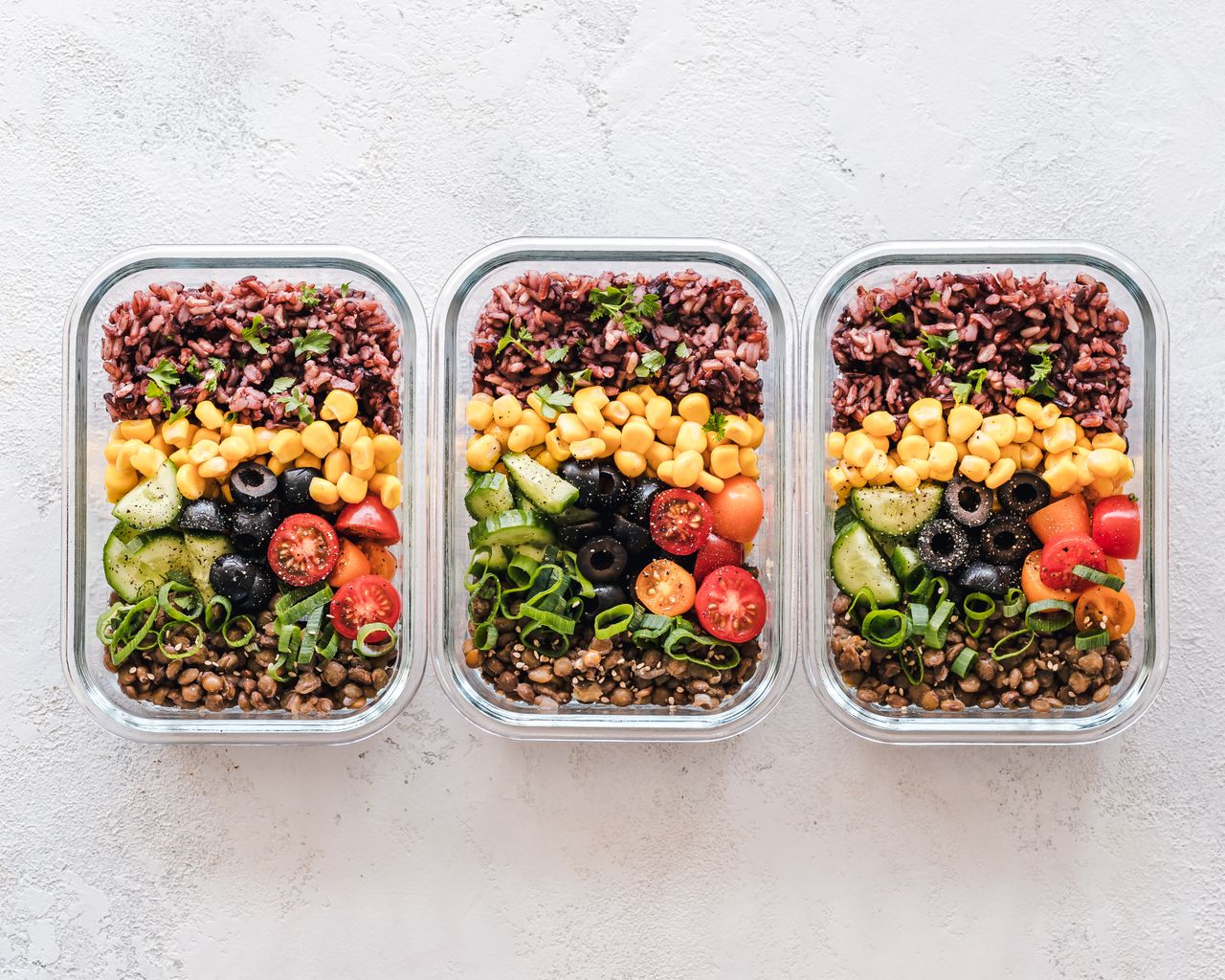 services-01 Colorful healthy meal prep with corn, olives, tomatoes, and lentils in glass containers. Perfect for mindful eating.